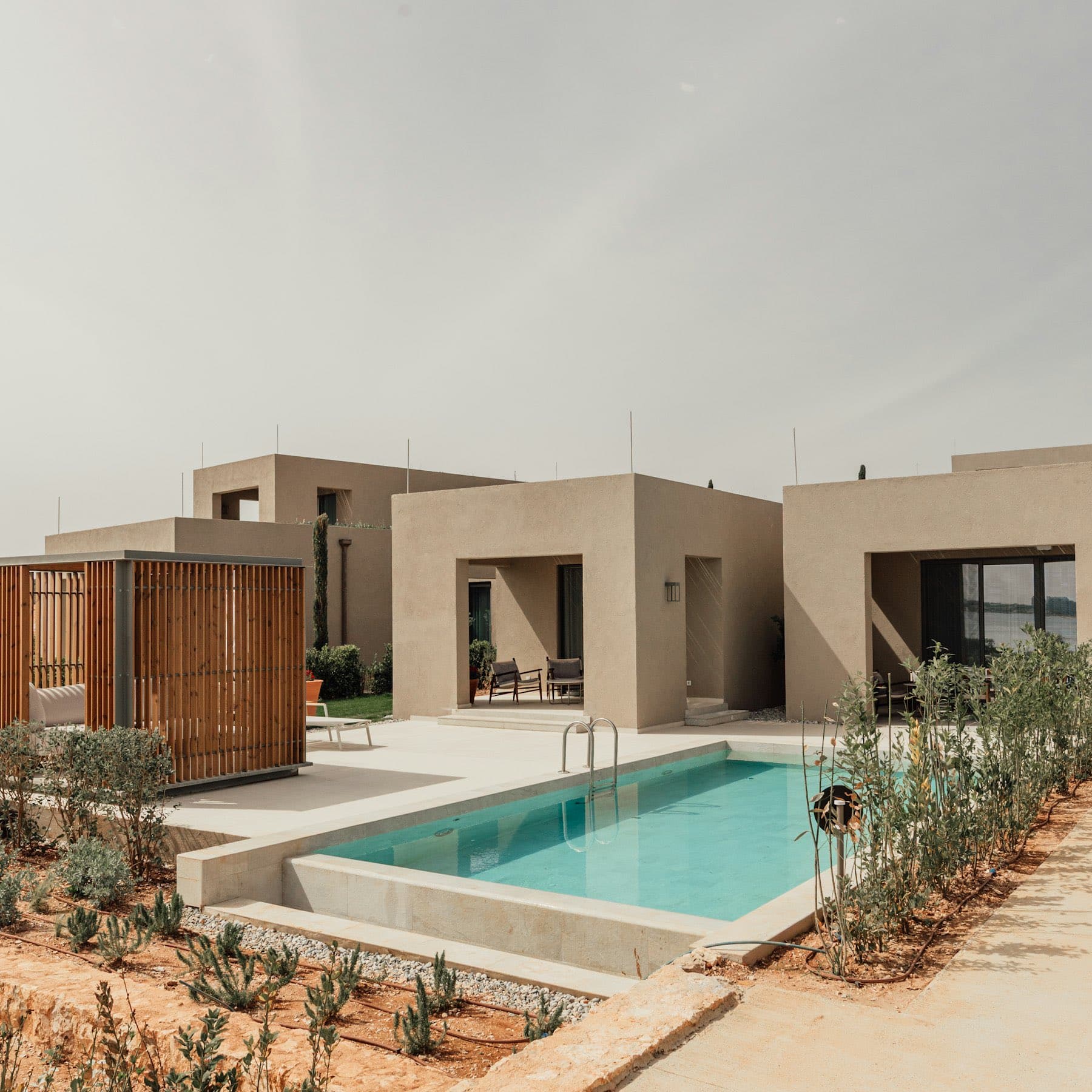 Concrete and timber facade with a side pool among planting