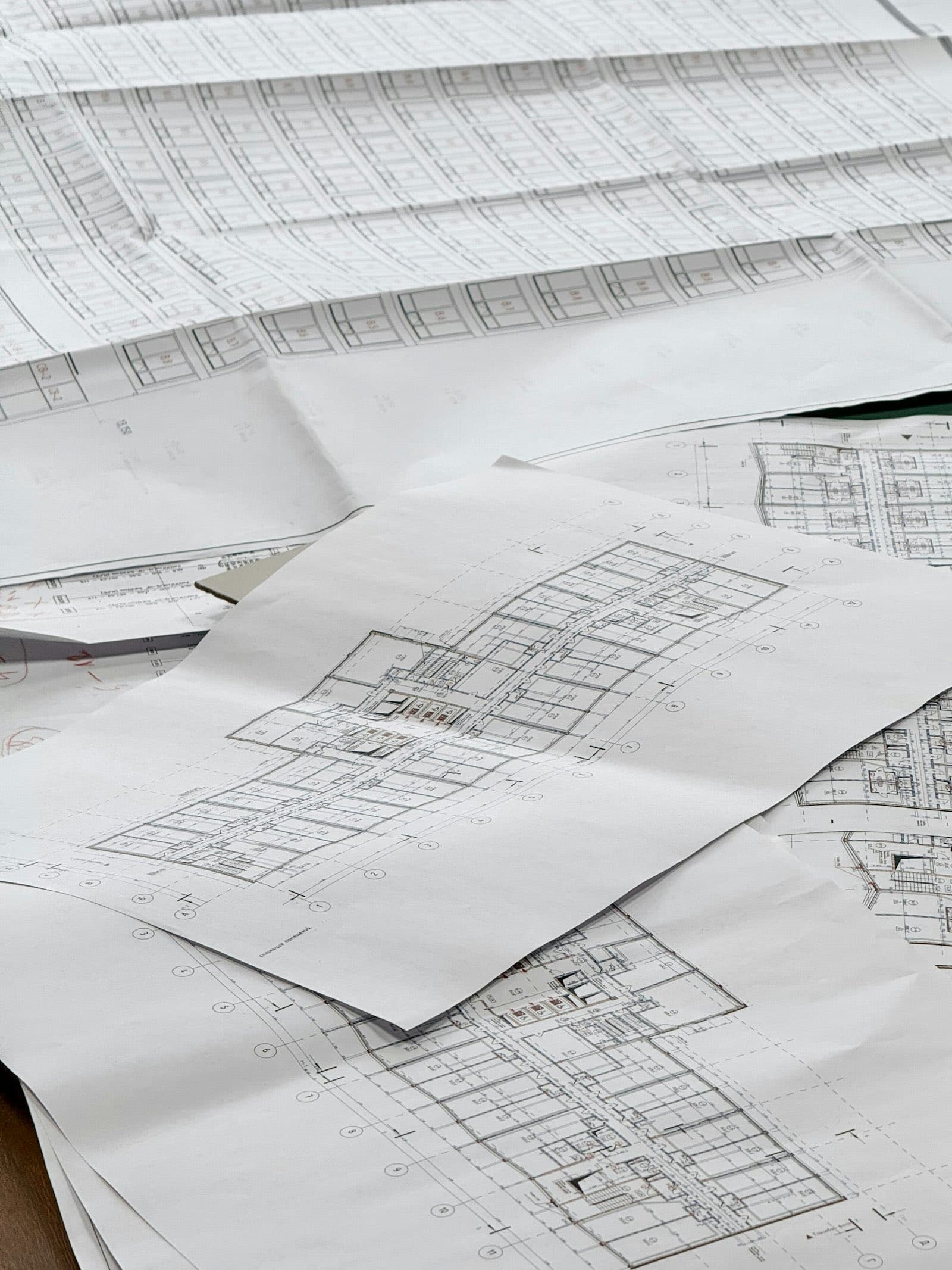 Planos arquitectónicos apilados sobre una mesa de trabajo