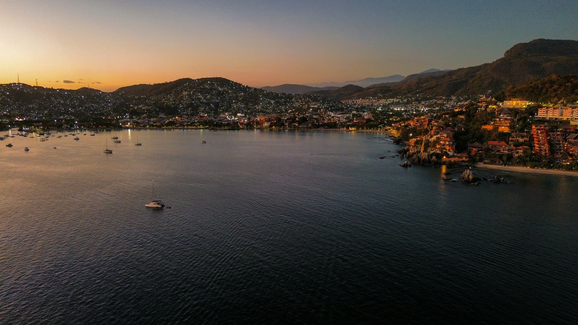 Bahía al atardecer con lanchas fondeadas frente al pueblo